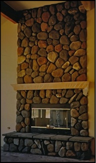 River rock masonry fireplace with slate covered hearth in room.
